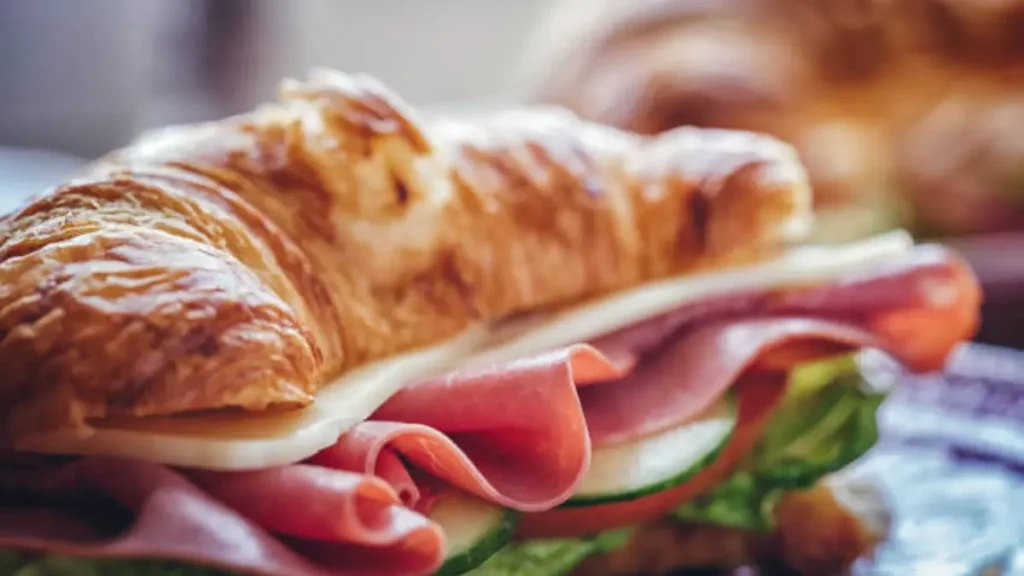 Golden, flaky Ham Cheese Croissant on a baking tray, with melted cheese peeking out and a shiny, egg-washed top. Perfectly warm and ready to serve