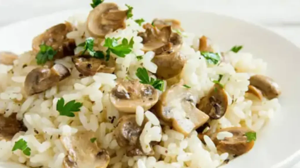 a plate of fluffy white Mushroom Ricemixed with sautéed mushrooms and garnished with fresh parsley