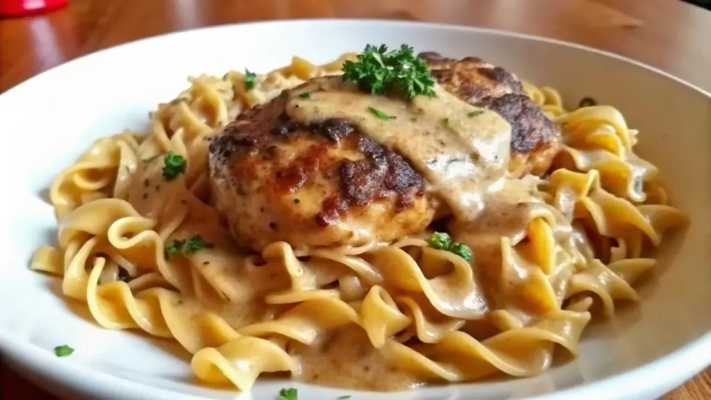 A plate of Chicken with buttered noodles, served over buttered egg noodles and garnished with parsley.