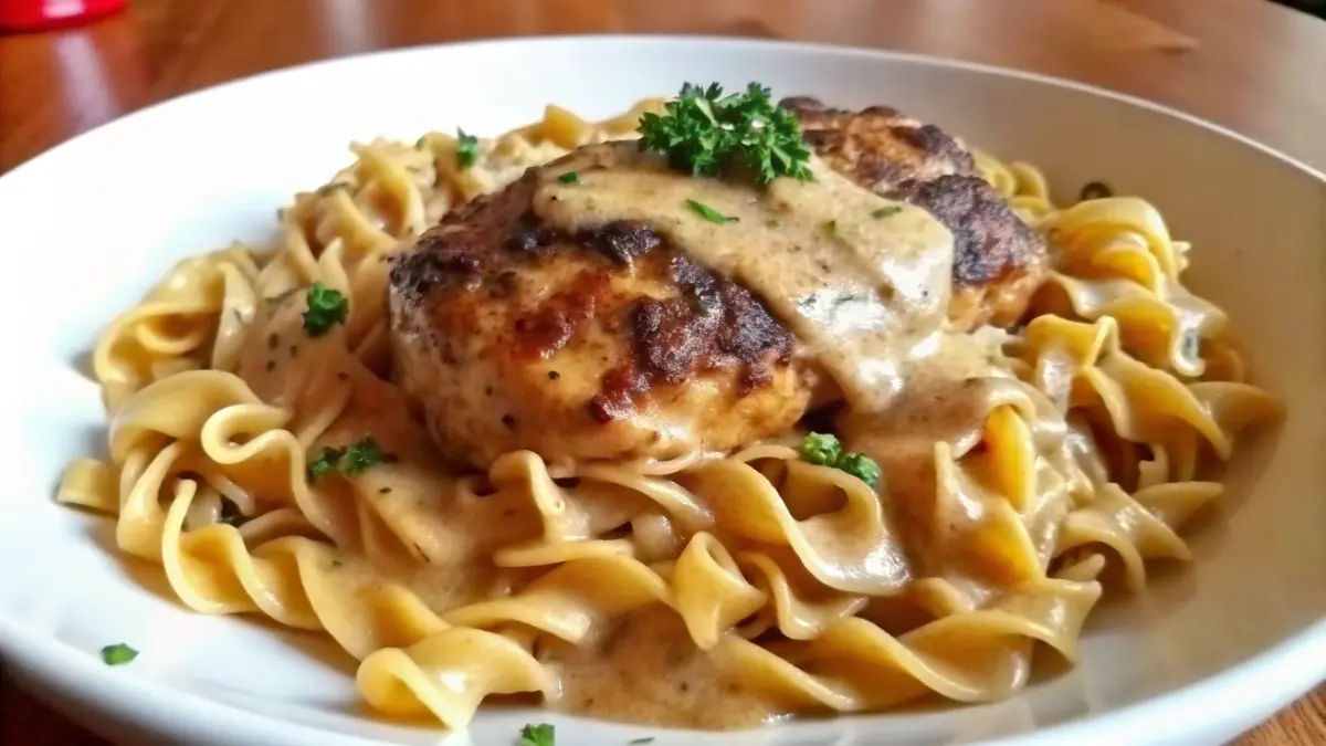 A plate of Chicken with buttered noodles, served over buttered egg noodles and garnished with parsley.